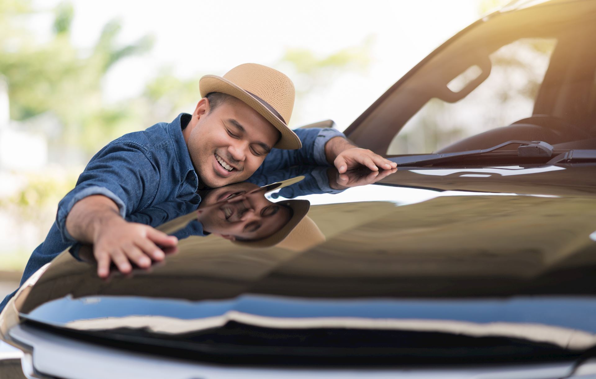 A man hugging his new car.