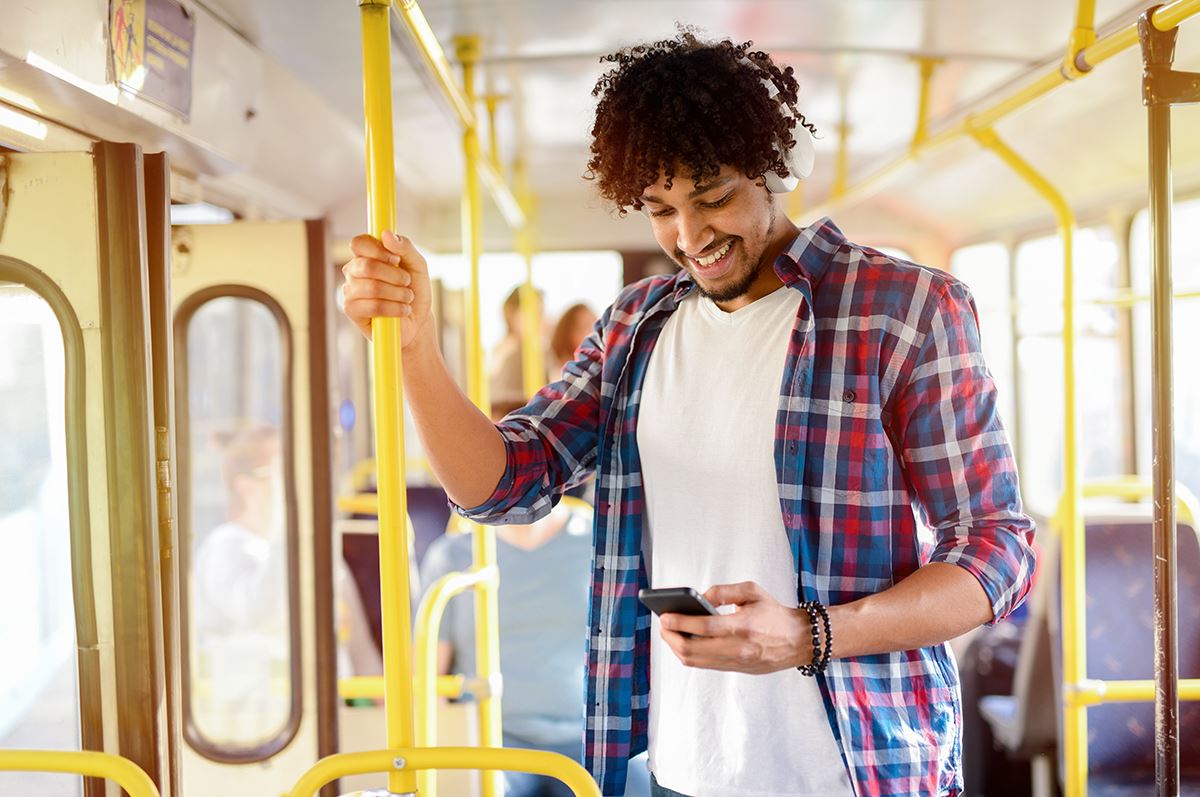 Man on public transportation looking at his cell phone.